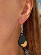 woman wearing black and gold teardrop shaped earring