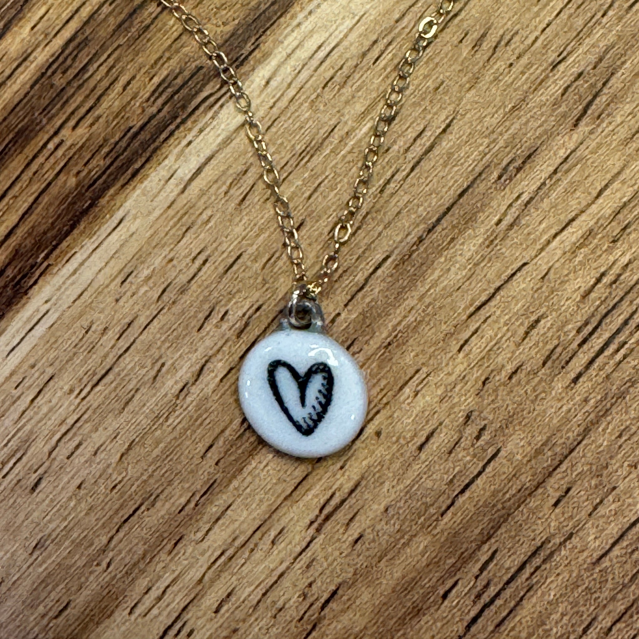 circular white necklace pendant with a black heart