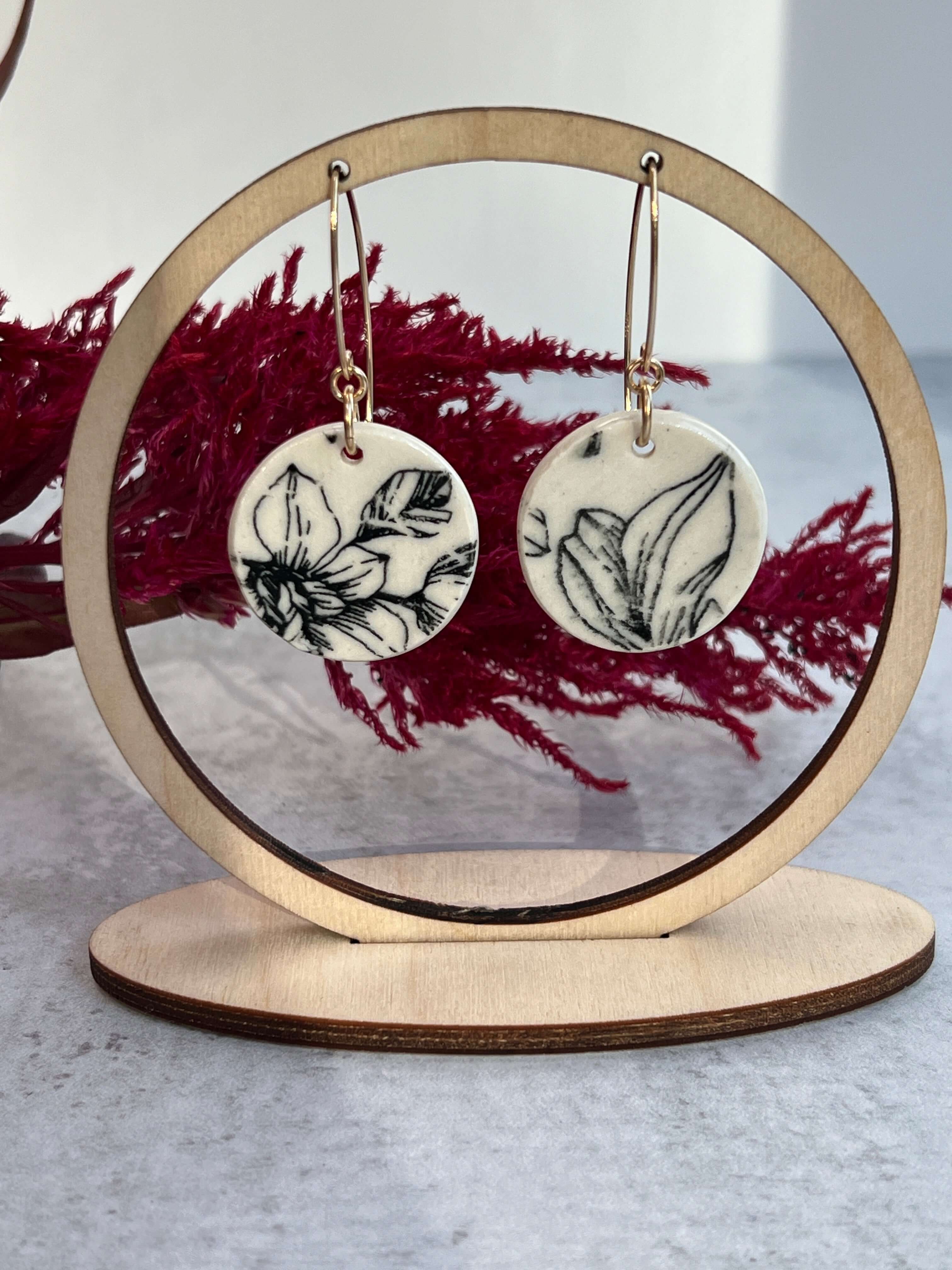 floral earrings hanging on a display with red background accent