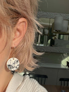 woman wearing circular black & white floral earring